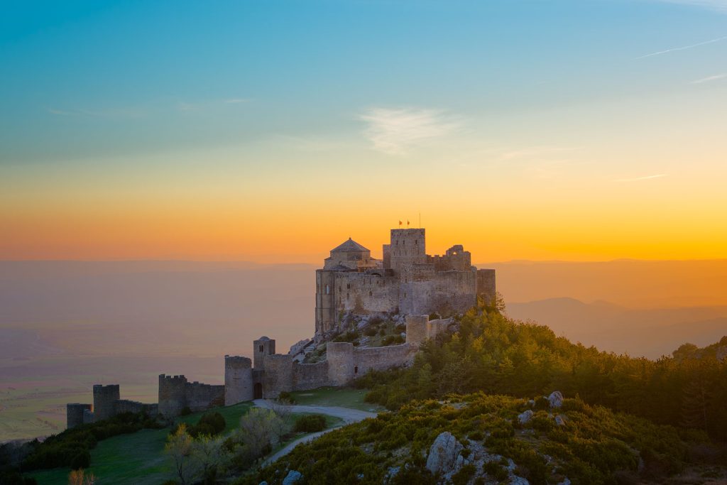 Castillo de Loarre sobre una colina, iluminado por la luz dorada del atardecer.